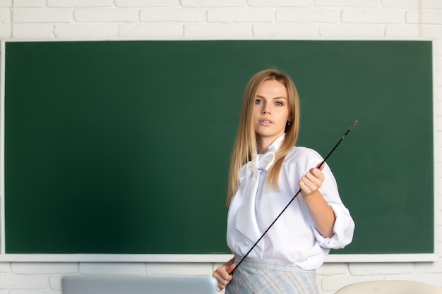 Junge ernsthafte Lehrerin zeigt auf Unterricht Süße junge Frau mit Zeigerunterricht in der Nähe der Tafel