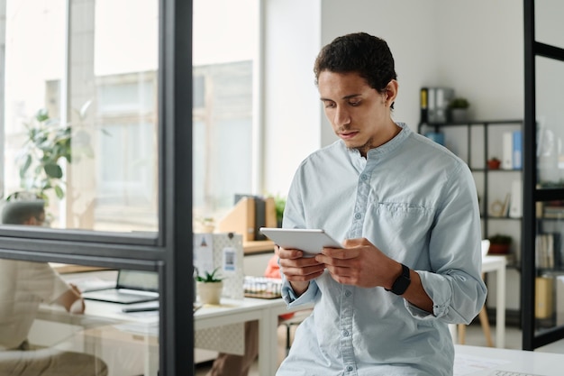 Junge, ernsthafte männliche Analyst mit Tablet