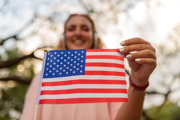 Junge erstaunliche Frau, die amerikanische Flagge hält