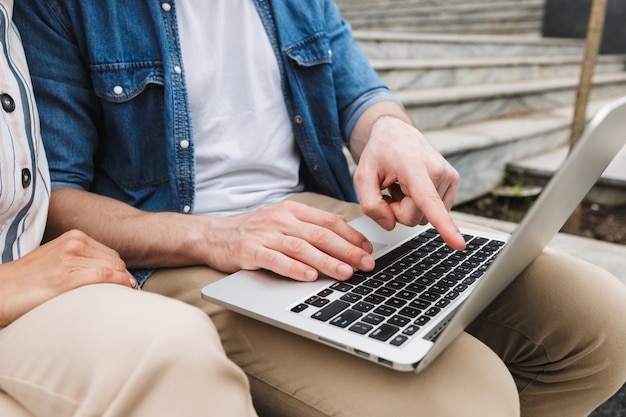 Foto junge erstaunliche liebespaar geschäftsleute kollegen im freien draußen auf stufen mit laptop-computer.