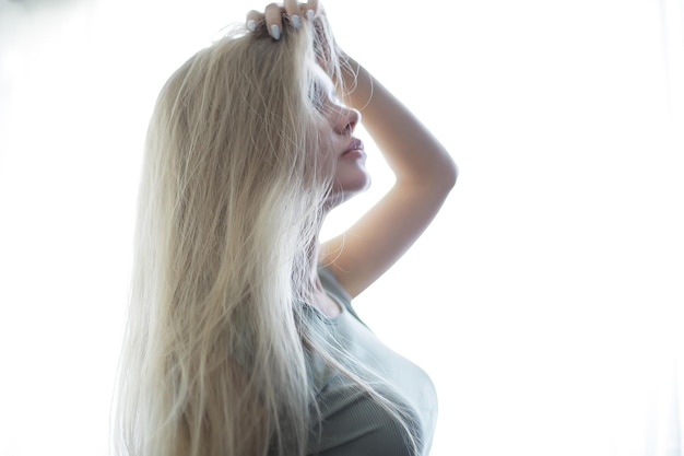 junge erwachsene blonde lange haare zu hause, stylisches modell posiert im studio