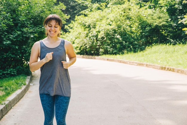 Junge erwachsene Frau, die durch den Stadtpark läuft, mit gesundem Lifestyle-Konzept der Musik