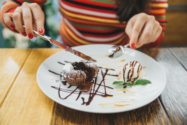 Junge erwachsene Frau, die Schokoladenfondant im Café isst