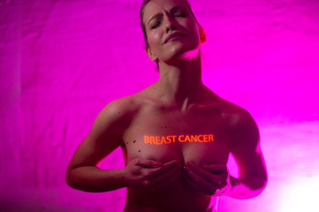Junge erwachsene Frau mit Worten Brustkrebs auf ihrer Brust mit Muttermalen
