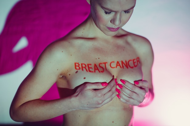 Junge erwachsene Frau mit Worten Brustkrebs auf ihrer Brust mit Muttermalen