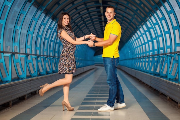Junge erwachsene Paare, die ihre Liebe genießen und in einem futuristischen blauen Tunnel posieren