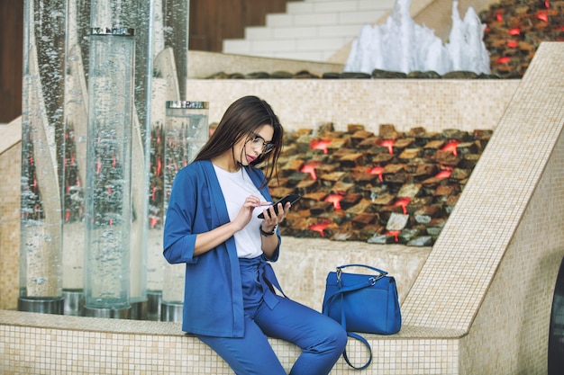 Junge erwachsene schöne brünette frau im businesscenter mit einem handy in ihren händen