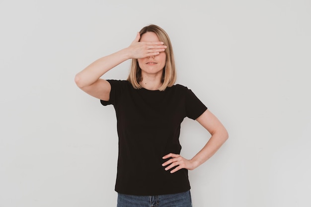 Junge europäische Frau im schwarzen T-Shirt, während sie ihre Augen mit der Hand bedeckt