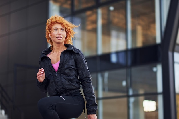 Junge europäische rothaarige Frau in sportlicher Kleidung beim Fitness im Freien