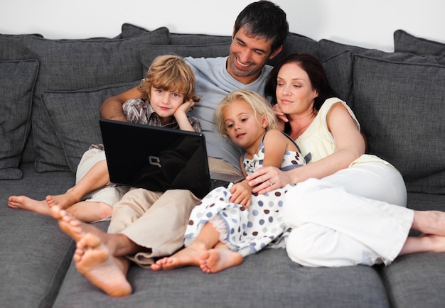 Foto junge familie auf einem sofa mit einem laptop