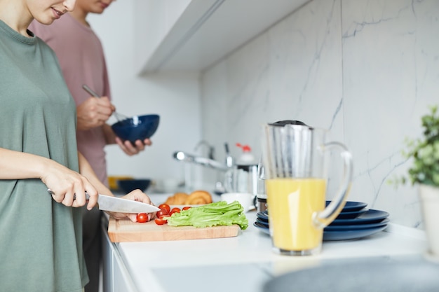 Junge Familie, die durch Küchentisch steht und Frühstück kocht