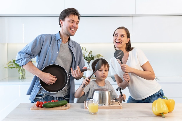 Junge Familie, die in der Küche Spaß hat, tanzt und singt