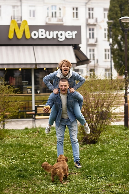 Junge Familie, die mit einem Hund durch die Stadtstraßen geht