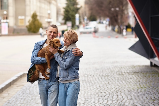 Junge Familie, die mit einem Hund durch die Stadtstraßen geht