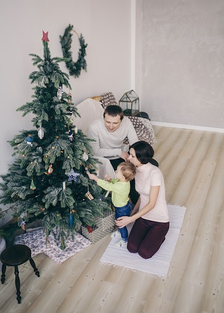 Junge Familie, die nahe Weihnachtsbaum sitzt