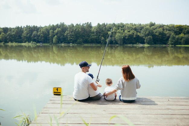 Junge Familie, Frau, Mann und zwei kleine Kinder, die am See angeln, Mann und Frau verbringen ein schönes Wochenende zusammen