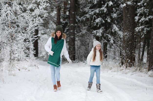 Junge Familie für einen Spaziergang. Mutter und Tochter gehen in einem Winterpark spazieren.