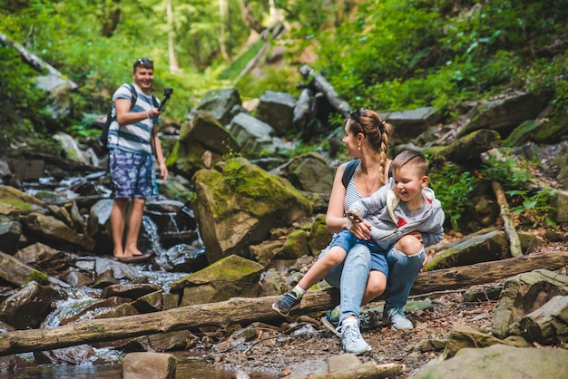 Junge Familie in der Nähe von Forest River Dad zeichnet Video zum Reisekonzept der Action-Kamera auf