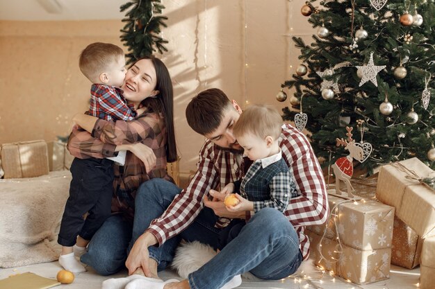 Junge Familie in karierten Hemden sitzt neben Weihnachtsbaum