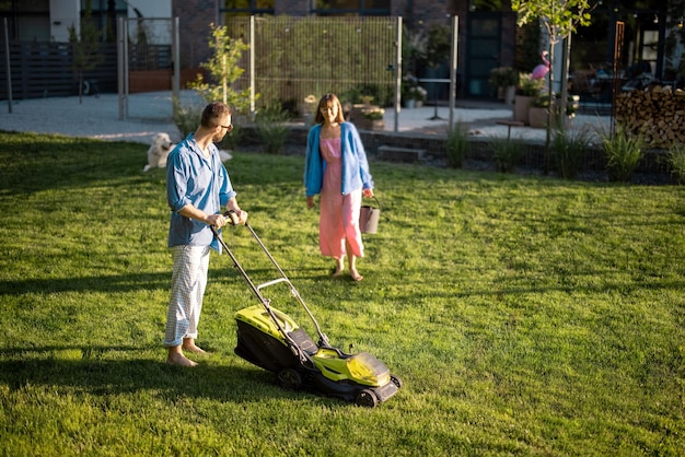 Junge Familie kümmert sich am Sommerabend um den Rasen