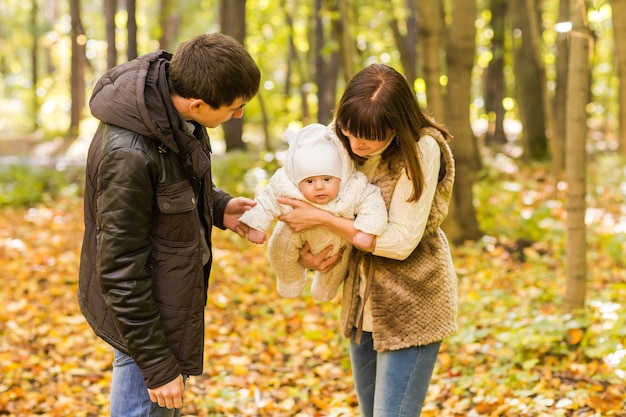 Junge Familie mit ihrem neugeborenen Baby, die Zeit im Freien im Herbstpark verbringt.