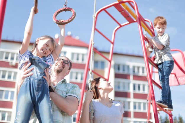 Junge Familie mit Kindern, die auf dem Spielplatz spielen, das Konzept der Kindheit und Elternschaft