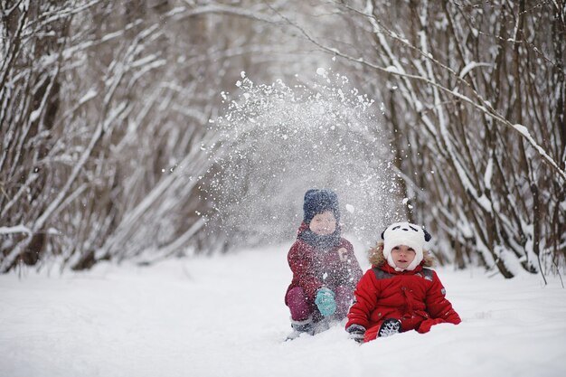 Junge Familie mit Kindern geht im Winterpark spazieren. Winterwanderung der Eltern mit Kindern. Wandern am Feiertagswochenende im Winter.