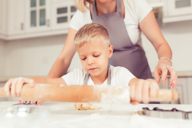 Junge Familie mit kleinen Kindern und Babysöhnen, die zu Hause Lebkuchenplätzchen machen.