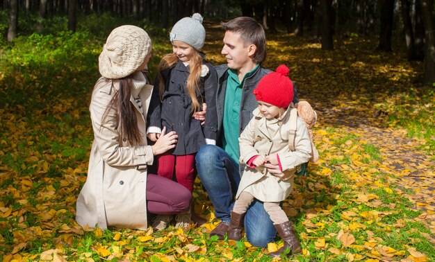 Junge Familie mit netten kleinen Mädchen im Herbstpark am sonnigen Tag