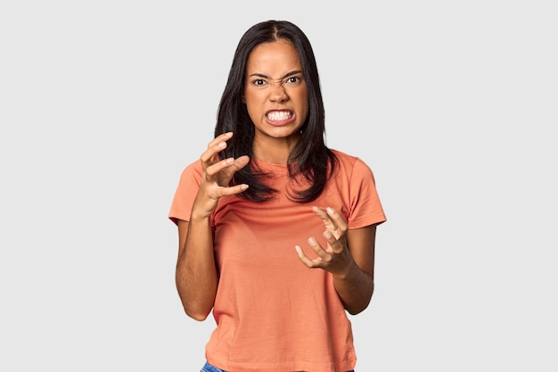 Junge Filipina mit langen schwarzen Haaren im Studio verärgert schreiend mit angespannten Händen
