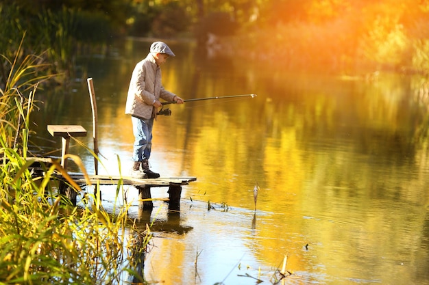 Junge fischt bei Sonnenuntergang auf dem See