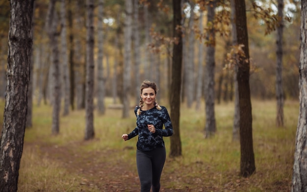 Junge fit Frau in Sportbekleidung läuft entlang Waldweg