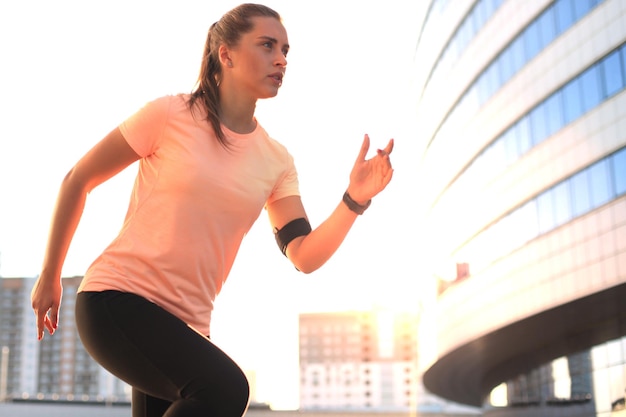 Junge Fitness attraktiver sportlicher Mädchenläufer in Startposition im Freien bei Sonnenuntergang oder Sonnenaufgang in der Stadt