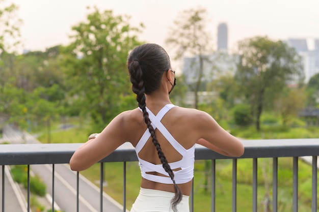 Junge Fitness-Frau in Sportbekleidung mit Gesichtsmaske beim Training im Stadtpark