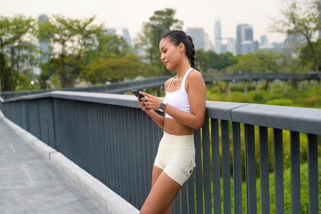 Junge Fitness-Frau in Sportbekleidung mit Smartphone beim Training in der Stadt