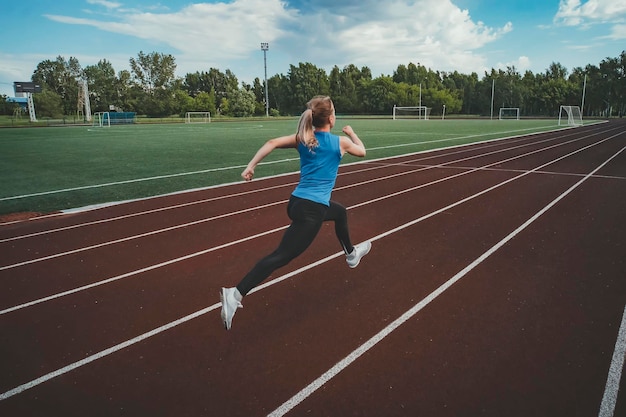 Junge Fitness-Läuferin, die auf der Stadionstrecke läuft Leichtathletik im Stadion