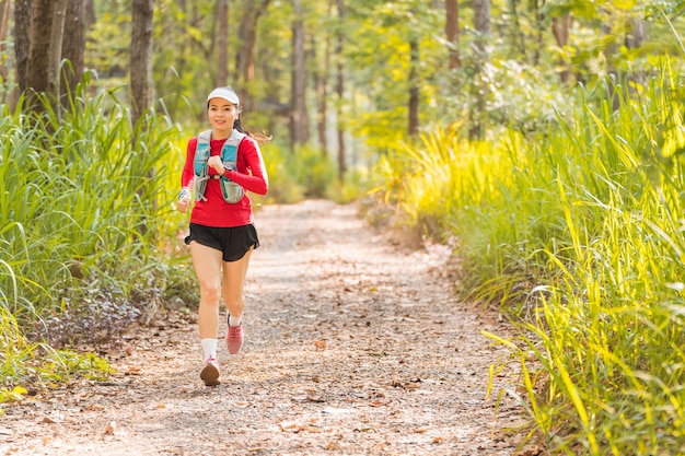 Junge Fitness-Sportlerin, die abends im tropischen Waldpark läuft