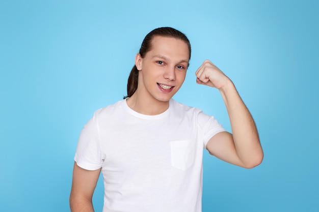 Junge Fitness starker Mann zeigt Bizepsmuskeln an Hand isoliert auf blauem Hintergrund.