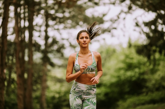 Junge Fitnessfrau, die am Waldweg läuft