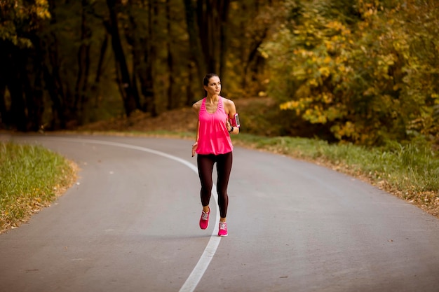 Junge Fitnessfrau, die am Waldweg läuft