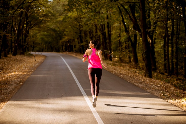 Junge Fitnessfrau, die am Waldweg läuft