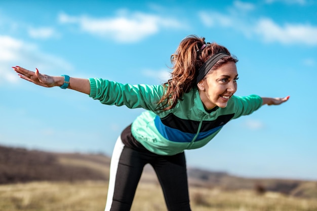 Junge Fitnessfrau, die nach dem Joggen in der Natur Dehnübungen macht.