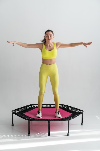 Junge Fitnessfrau in Sportkleidung, die auf Sporttrampolin springt