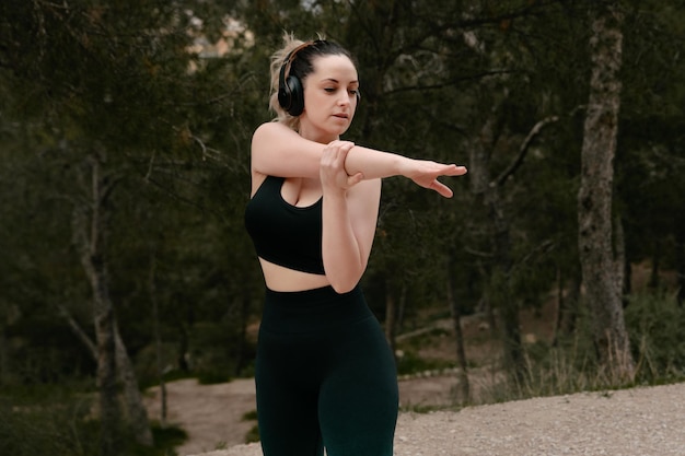 Junge Fitnessfrau macht Dehnübungen im Freien