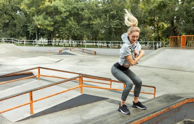 Junge, fitte Blondine springen im Freien. Sporttrainingskonzept