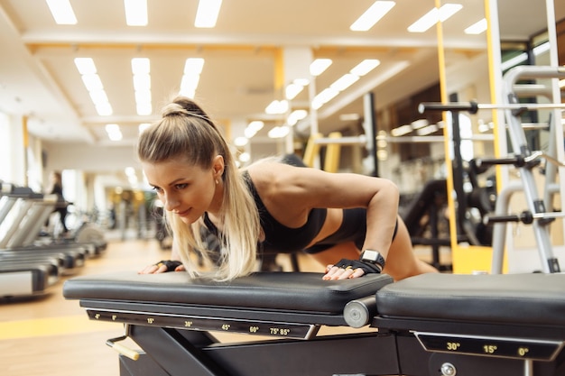 Junge fitte Frau macht Liegestütze von der Bank im Fitnessstudio Gesunder Lebensstil