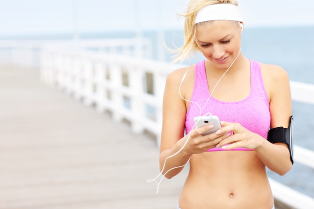 Junge fitte Frau mit Telefon auf dem Pier