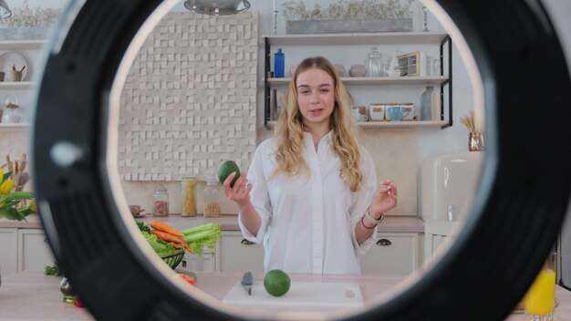 Junge Food-Bloggerin kocht Salat vor der Smartphone-Kamera, während sie zu Hause in der Küche Vlog-Videos und Live-Streaming aufnimmt