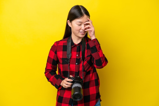 Junge Fotografin Chinesin isoliert auf gelbem Hintergrund lachend