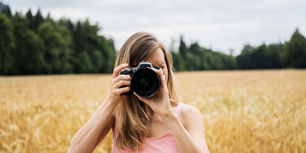 Junge Fotografin, die ein Foto in Richtung der Kamera macht, die Fokus auf ihrem Objektiv anordnet.